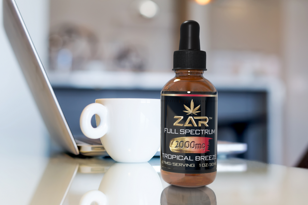 CBD tincture next to a coffee cup and laptop